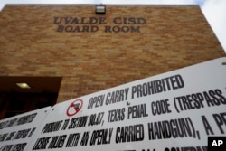 Signs prohibiting guns are displayed outside the Uvalde Consolidated Independent School District boardroom where District Superintendent Dr. Hal Harrell provided an update following the recent shooting at Robb Elementary, June 9, 2022, in Uvalde, Texas.