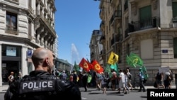 A police officer stands guard as people attend a demonstration ahead of the upcoming World Trade Organization (WTO) ministerial meeting (MC12) in Geneva, Switzerland, June 11, 2022.