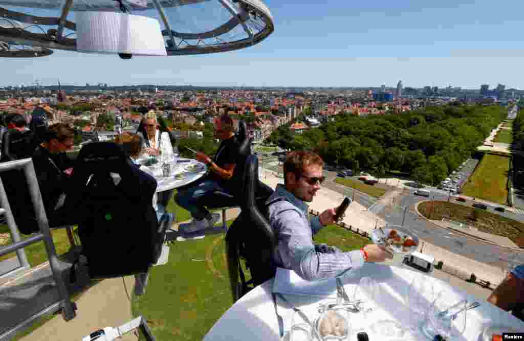 People sit at one of the eight tables on a structure, suspended from a crane at a height of 50 meters. It can hold a total of 32 guests for a meal during an event known as &quot;Dinner in the Sky&quot; outside Koekelberg Basilica in Brussels, Belgium. (REUTERS/Yves Herman )