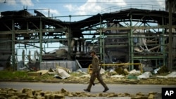 A Ukrainian serviceman walks past a gypsum manufacturing plant destroyed in a Russian bombing in Bakhmut, eastern Ukraine, eastern Ukraine, Saturday, May 28, 2022. Fighting has raged around Lysychansk and neighbouring Sievierodonetsk, the last major citie
