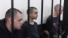 Dos ciudadanos británicos, Aiden Aslin (izq.) y Shaun Pinner (der.), y el marroquí Saaudun Brahim, (centro), tras las rejas en un tribunal en Donetsk, bajo el control del autoproclamado Gobierno de la República Popular de Donetsk, en el este de Ucrania, el 9 de junio de 2022.