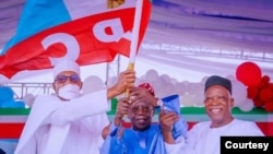 Le président sortant Muhammadu Buhari (à g.) présente le drapeau du parti au pouvoir à Bola Tinubu (au centre), vainqueur des primaires du parti, le 6 juin 2022.