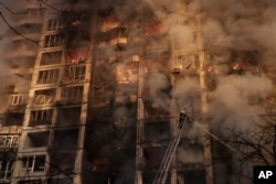 Ukrainian firefighters work at a bombed apartment building in Kyiv, Ukraine, Tuesday, March 15, 2022.