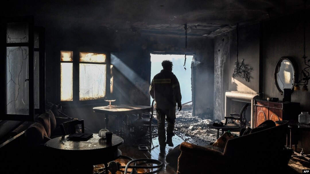A firefighter inspects damage at a partially burned house in Panorama Voulas, south of Athens, June 4, 2022.
