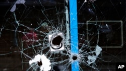 FILE - A storefront window with bullet holes is seen at the scene of a fatal shooting on South Street in Philadelphia, Pennsylvania, June 5, 2022.