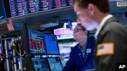 In this photo provided by the New York Stock Exchange, specialist Patrick King, left, works a his post on the floor, June 13, 2022. (Courtney Crow/New York Stock Exchange via AP)