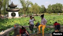 FILE - People enjoy themselves by the lakeside at a park during the Dragon Boat festival holiday, following the COVID-19 outbreak in Beijing, China, June 4, 2022.