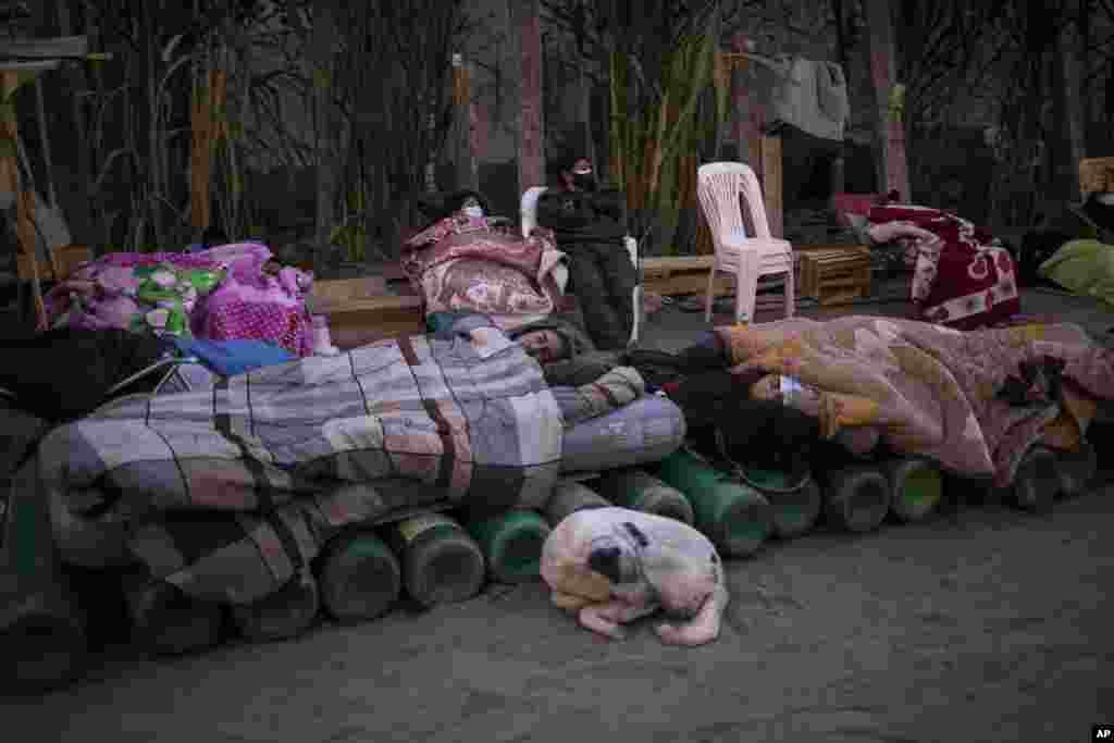 People sleep on top of empty oxygen cylinders, waiting for a shop to open in order to refill their tanks, in the Villa El Salvador neighborhood, as the lack of medical oxygen to treat COVID-19 patients continues in Lima, Peru, April 6, 2021.