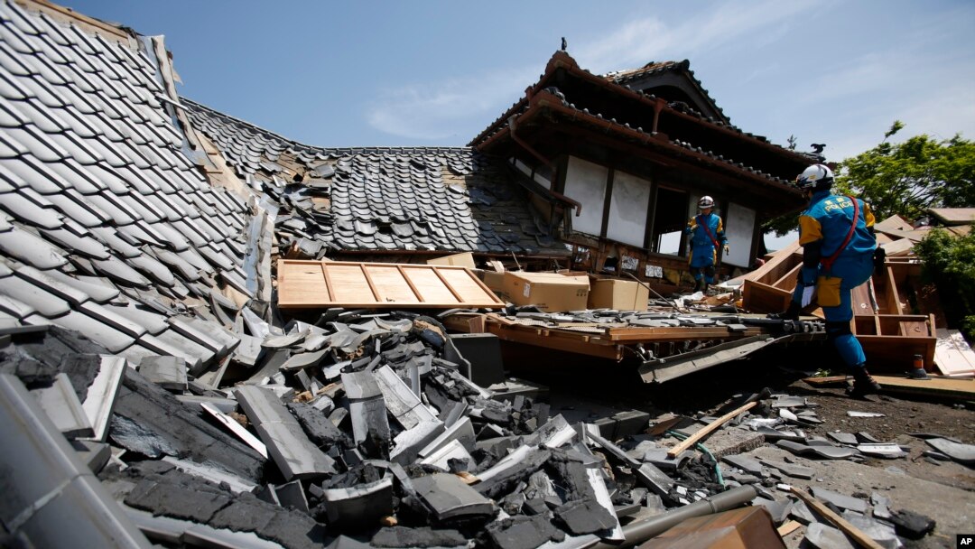 Equipos de rescate buscan personas atrapadas entre casas destruidas por el terremoto en Kumamoto, sur de Japón, el viernes, 15 de abril de 2016.