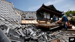 Equipos de rescate buscan personas atrapadas entre casas destruidas por el terremoto en Kumamoto, sur de Japón, el viernes, 15 de abril de 2016.