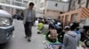 FILE - A Chinese man looks at Uighur people as they pray at a mosque in Shanghai, April 11, 2014.