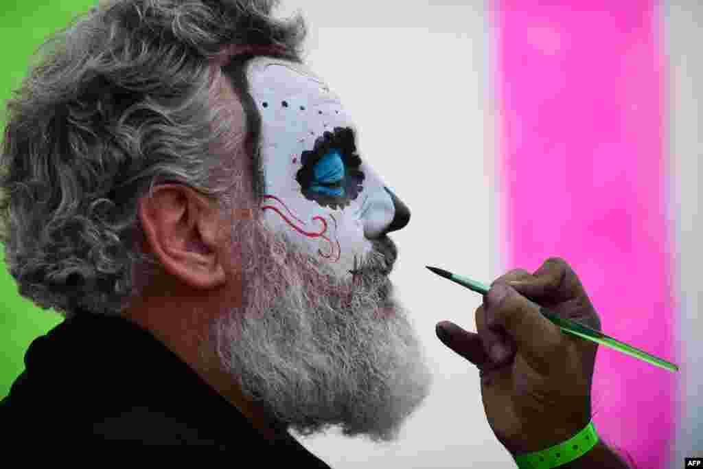 A man has his face painted during celebrations in the framework of the Day of the Dead at the Hermanos Rodriguez racetrack in Mexico City.