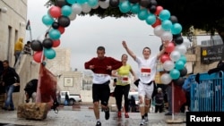 Para peserta lomba lari maraton internasional pertama di Palestina mencapai garis finis di kota Betlehem, Tepi Barat, Minggu (21/4).
