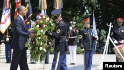 A member of an honor guard helps U.S. President Barack Obama (L) lay a wreath in honor of Memorial Day at the Tomb of the Unknowns in Arlington National Cemetery in Arlington, Virginia, May 28, 2012