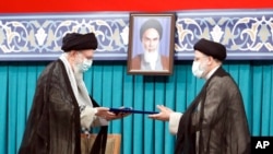 Supreme Leader Ayatollah Ali Khamenei, left, gives his official seal of approval to newly elected President Ebrahim Raisi, in Tehran, Iran, Aug. 3, 2021, in this photo released by an official website of the office of the Iranian supreme leader.