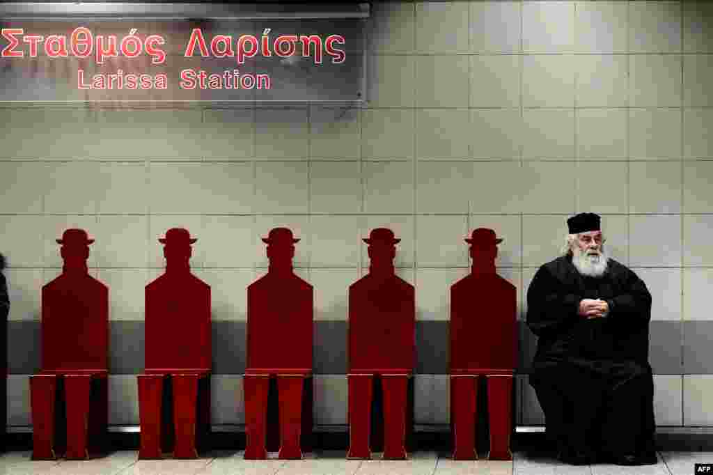 A Greek Orthodox priest sits on a platform at the Athens&#39; Larissa metro station. 