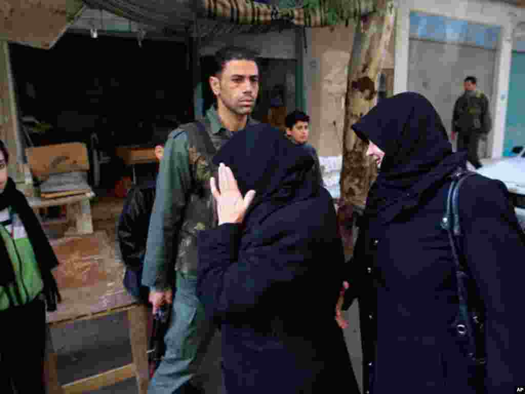 Women walk past a Syrian soldier outside Damascus in Harasta, January 26, 2012. (Reuters)