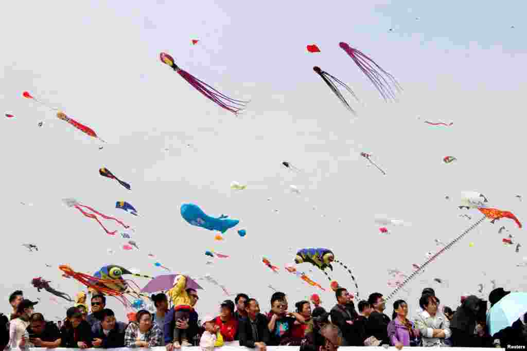 People look at the kites in various shapes flying in the sky during the International Kite Festival in Weifang, Shandong province, China, April 20, 2019.