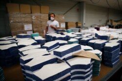 In this June 12, 2020 photo, an employee walks by fabric cut to produce face protection masks in Chanteclair Hosiery, a French knitwear clothing manufacturer, in Saint Pouange, east of Paris.