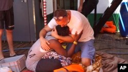 A migrant is comforted by a crew member of the Open Arms Spanish humanitarian boat off the coast of the Sicilian island of Lampedusa, southern Italy, Sunday, Aug.18, 2019. 