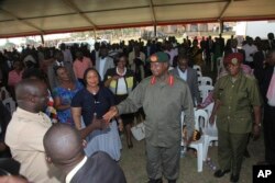 FILE - Uganda President Yoweri Museveni, center in military uniform, greets relatives of prison wardens during a graduation ceremony in the capital Kampala Thursday Jan. 18, 2018.