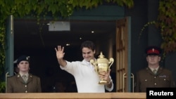 Roger Federer of Switzerland holds the winners trophy on the clubhouse balcony after defeating Andy Murray of Britain in their men's singles final tennis match at the Wimbledon Tennis Championships in London, July 8, 2012.