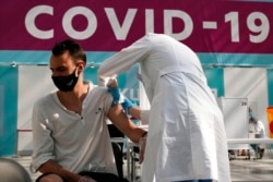 FILE - In this July 12, 2021, photo, a medical worker administers a shot of Russia's Sputnik V coronavirus vaccine at a vaccination center in Gostinny Dvor, a huge exhibition place in Moscow.