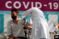 FILE - In this July 12, 2021, photo, a medical worker administers a shot of Russia's Sputnik V coronavirus vaccine at a vaccination center in Gostiny Dvor, a sprawling exhibition space in Moscow.