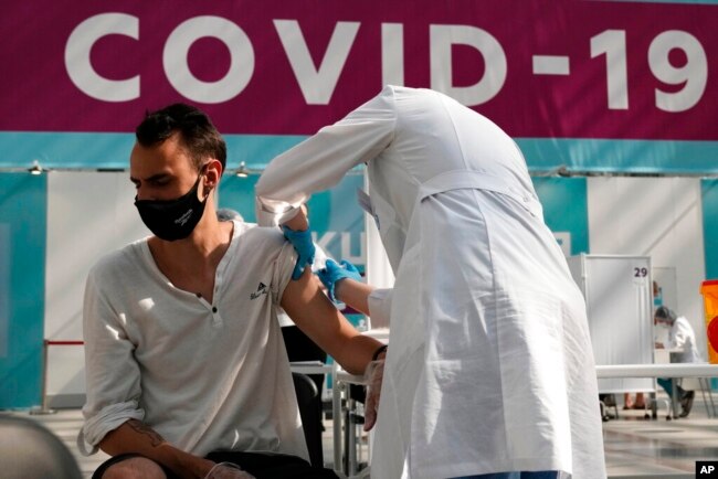 FILE - In this July 12, 2021, photo, a medical worker administers a shot of Russia's Sputnik V coronavirus vaccine at a vaccination center in Gostinny Dvor, a huge exhibition place in Moscow.