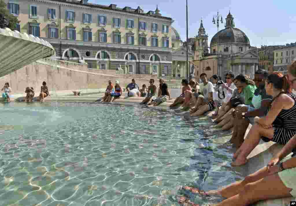 Tourists cool off in the Goddess of Rome fountain, in Rome. A heat wave with temperatures as high 35 degrees Celsius, 95 Fahrenheit, is crossing Italy from north to south.