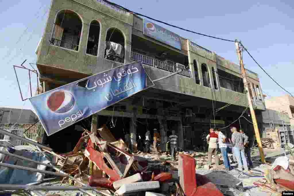 Residents gather at the premises of a coffee shop that was destroyed in a suicide bomb attack the night before, in Baghdad, June 17, 2013.