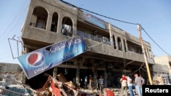 Residents gather at the premises of a coffee shop that was destroyed in a suicide bomb attack the night before, in Baghdad, June 17, 2013. 