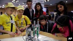 In this Nov. 27, 2016 photo, participants and spectators look at a 3D printer made of LEGO parts during the World Robot Olympiad in New Delhi, India. The weekend games brought more than 450 teams of students from 50 countries to the Indian capital.