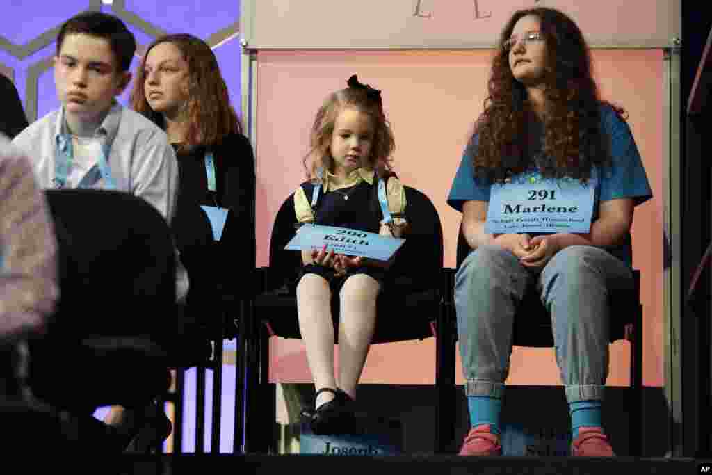 Edith Fuller, 6, of Tulsa, Okla., center, the youngest speller ever in the National Bee, sits with other spellers as they wait to compete in the 90th Scripps National Spelling Bee in Oxon Hill, Maryland.