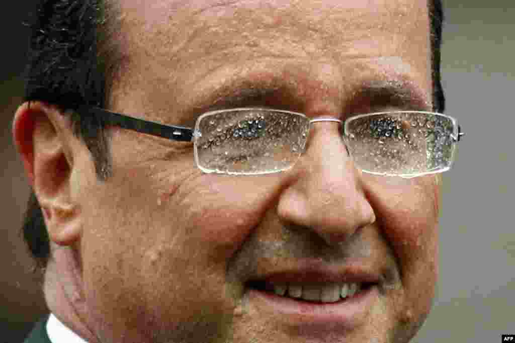 Hollande smiles from his car as he drives down the Champs Elysees avenue during a rain shower. (AP)