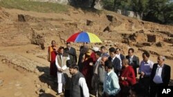 Tibetan spiritual leader the Dalai Lama, center holding umbrella, accompanied by officials visits a Buddhist heritage site in village Ambaran in Akhnoor, Jammu-Kashmir state, India, Wednesday, Nov. 16, 2011.