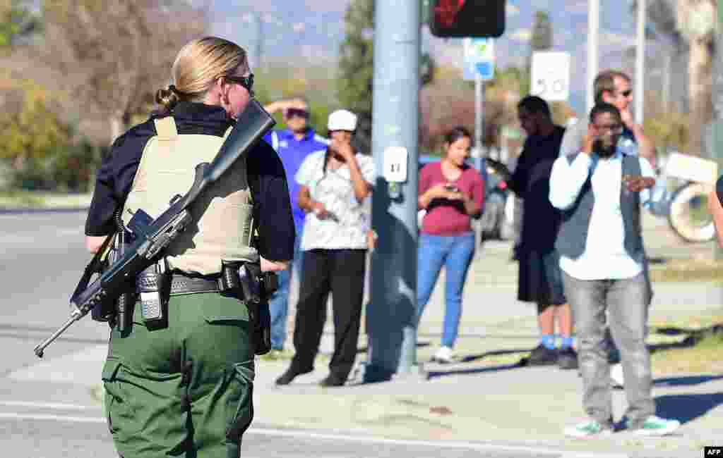 A heavily armed officer sets up a perimeter near the site of the shootings.