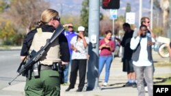 A heavily armed officer sets up a perimeter near the site of the shootings.