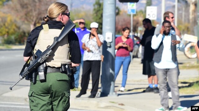 Una oficial de policía fuertemente armada establece el perímetro alrededor del sitio del tiroteo en San Bernardino, California.