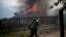 A pro-Russian armed man runs past a burning house after it was set on fire by a mortar shell, on the outskirts of the town of Lysychansk, Ukraine, May 22, 2014. 