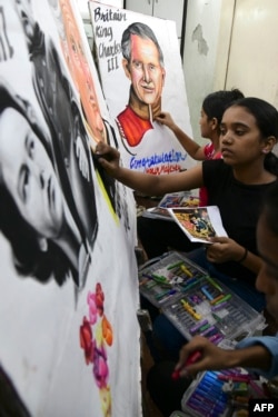 Estudiantes de arte dan los toques finales a las pinturas realizadas como homenaje de felicitación al Príncipe Carlos III de Gran Bretaña por su acceso al trono, en Mumbai el 11 de septiembre de 2022. (Foto de Sujit JAISWAL / AFP)