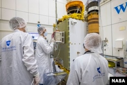 FILE - DART team members from the Johns Hopkins Applied Physics Laboratory in Maryland and the Italian Space Agency carefully position the LICIACube into place on the DART spacecraft. (NASA/Johns Hopkins APL/Ed Whitman)