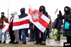 Pendukung oposisi memegang bekas bendera putih-merah-putih Belarus saat mereka berkumpul untuk memprotes kekerasan polisi dan hasil pemilihan presiden Belarus di Minsk, pada 29 November 2020. (Foto: AFP)