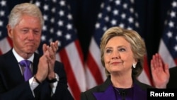 FILE - Hillary Clinton, with her husband, former U.S. President Bill Clinton, left, receives applause at her concession speech to President-elect Donald Trump in New York, Nov. 9, 2016. Hillary Clinton won the popular vote but Trump won the Electoral College.