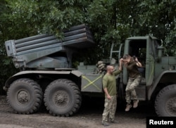 Ukrainian servicewoman Tetyana Dovgopola is helped by her serviceman husband Andrij Dovgopolyi as she jumps out their squad's BM21 Grad multiple rocket launcher at a position near a frontline in Mykolaiv region, Ukraine, Sept. 16, 2022.