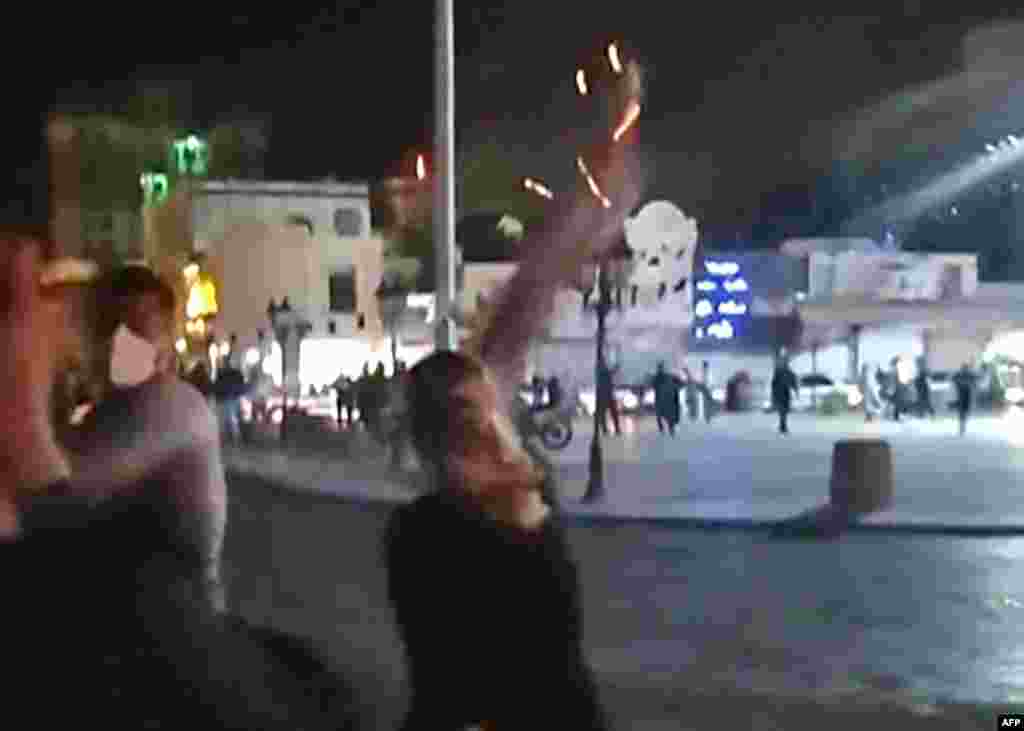 This grab taken from a UGC video and dated to Sept. 25, 2022 shows an Iranian protester throwing her burning headscarf in Iran's southwestern city of Bushehr. 