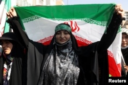 An Iranian pro-government woman holds the Iranian flag during a rally against the recent protest gatherings in Iran, in Tehran, Sept. 23, 2022. (Majid Asgaripour/WANA via Reuters)