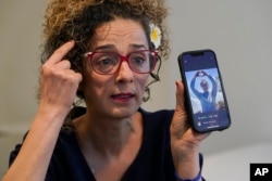 FILE -Iranian dissident Masih Alinejad hold up a photo of an Iranian woman who was killed during the current protests in Iran, as she speaks during an interview with The Associated Press, in New York, Sept. 23, 2022.