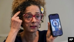 FILE - Iranian dissident and VOA Persian television host Masih Alinejad hold up a photo of an Iranian woman who was killed during the current protests in Iran, as she speaks during an interview with The Associated Press, in New York, Sept. 23, 2022.
