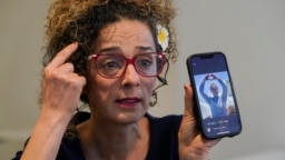 FILE - Iranian dissident and VOA Persian television host Masih Alinejad hold up a photo of an Iranian woman who was killed during the current protests in Iran, as she speaks during an interview with The Associated Press, in New York, Sept. 23, 2022.